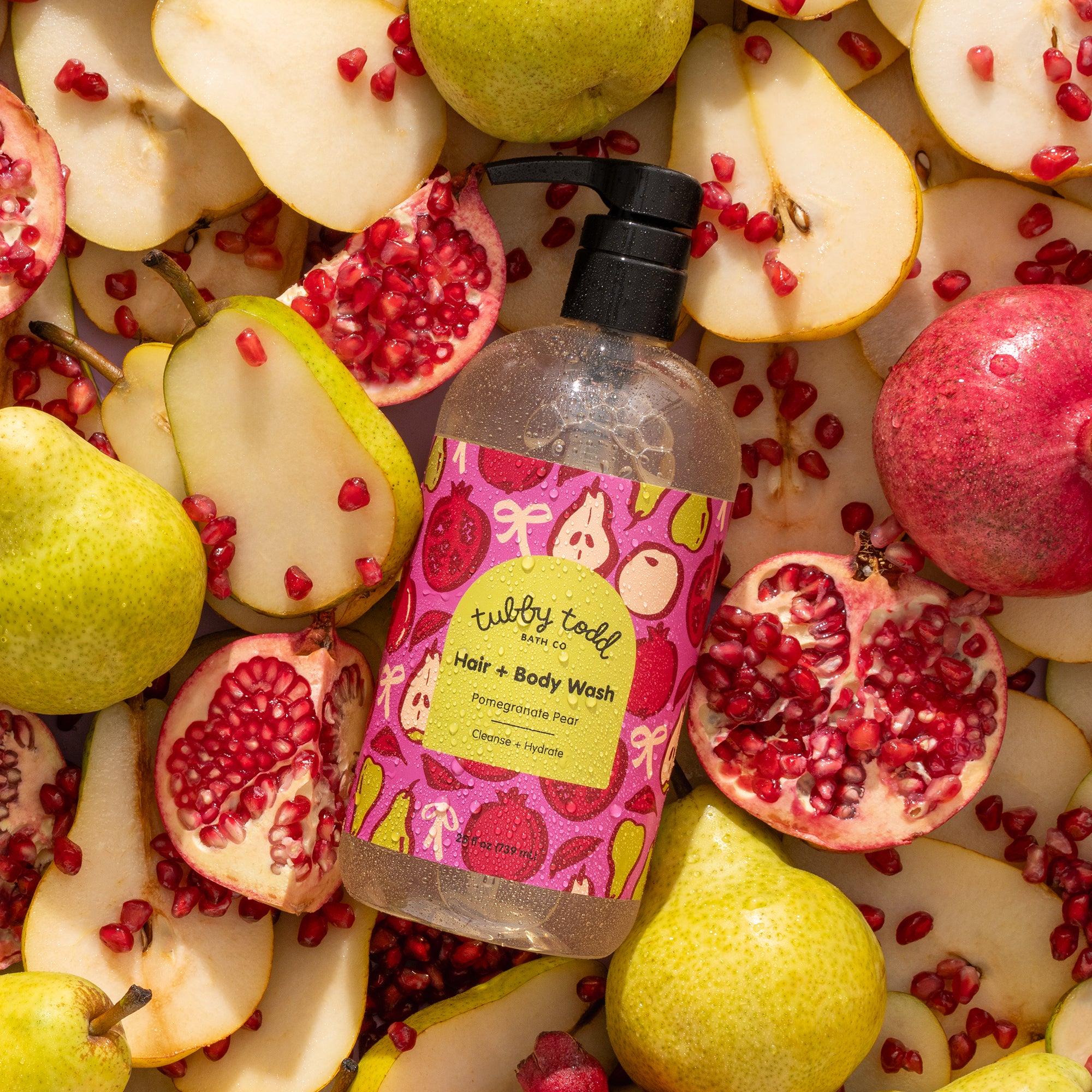 Pom Pear Hair + Body Wash 25oz bottle lying on the bunch of slices pears and pomegranates.